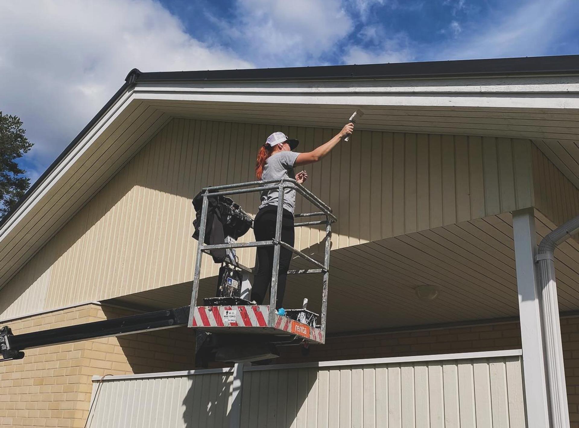 Starttimaalaus Oy:n yritt&auml;j&auml; Noora maalamassa talon ulkosivua.