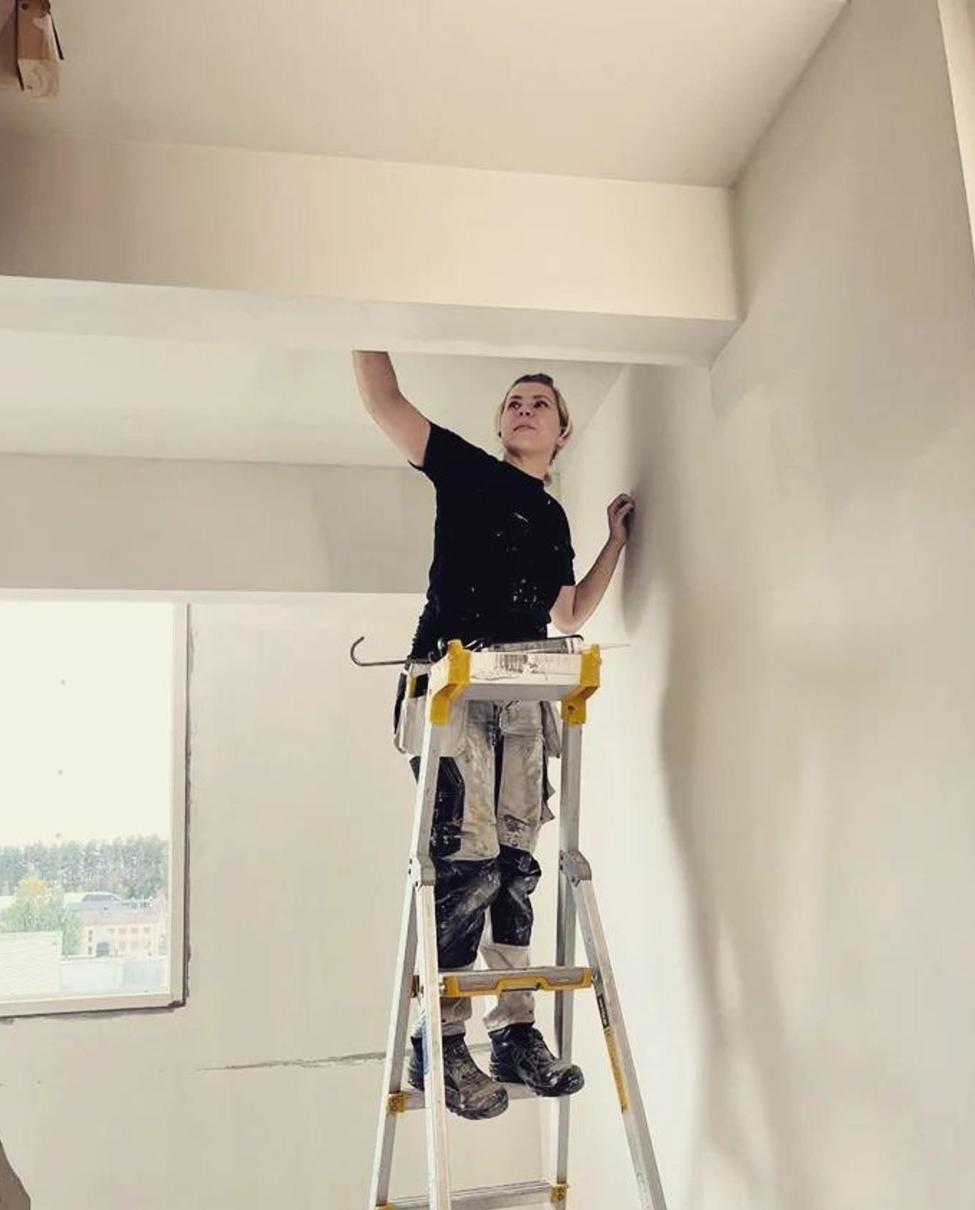 Starttimaalaus Oy:n yrittäjä Noora tekemässä tasoitetöitä tikkailla seisten.